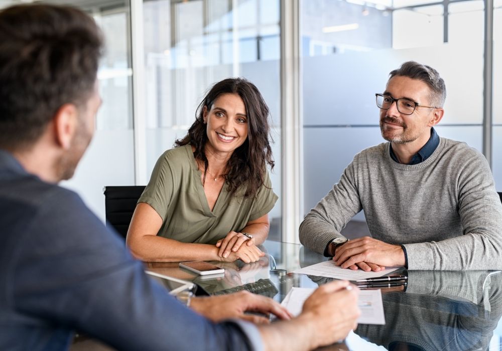 Group of professionals having a positive meeting around a glass table in a modern office setting.
