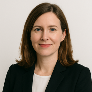 Professional woman in a black blazer smiling against a plain background.