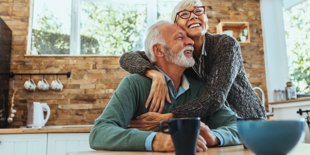 Happy senior couple embracing in cozy kitchen, enjoying morning coffee together.