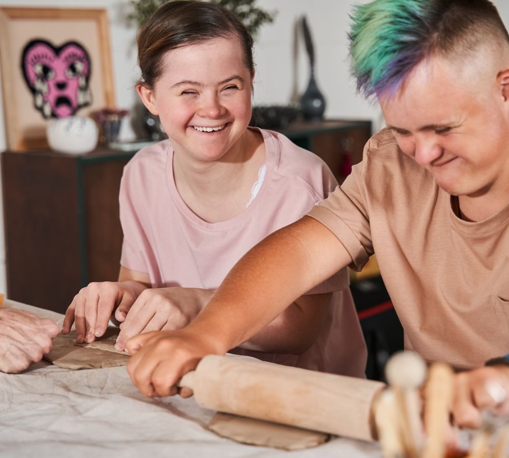 People happily crafting clay sculptures together in a creative class activity.