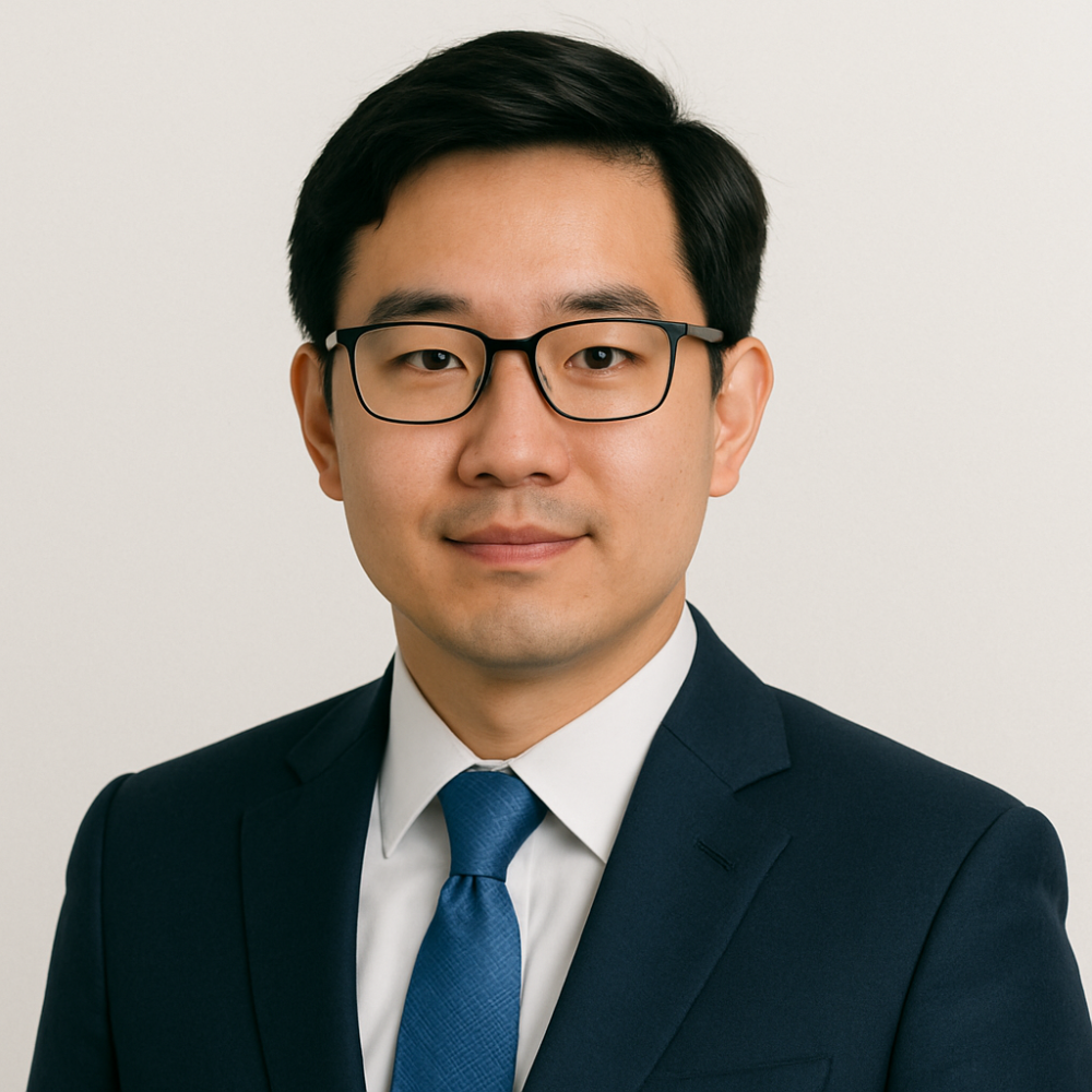 A professional man in a suit and glasses with a neutral background, suitable for business profile or portrait.